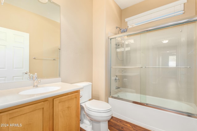 full bath with vanity, toilet, wood finished floors, and shower / bath combination with glass door