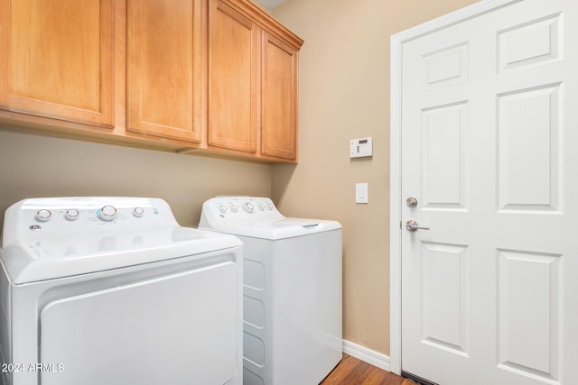 laundry room featuring wood finished floors, washing machine and dryer, cabinet space, and baseboards