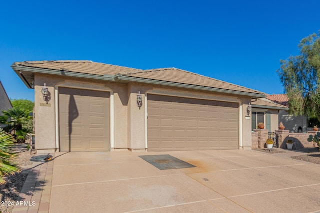 view of front of house with stucco siding, a garage, driveway, and a tiled roof