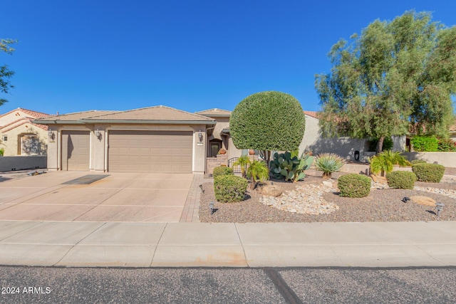 view of front of property with a tile roof, an attached garage, driveway, and stucco siding