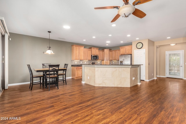 kitchen with light brown cabinetry, tasteful backsplash, dark countertops, dark wood-style floors, and appliances with stainless steel finishes