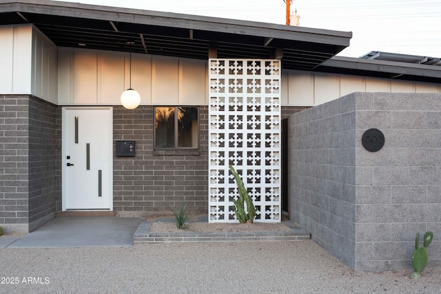 view of exterior entry featuring brick siding and board and batten siding