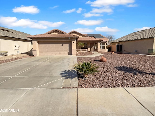 view of front of property featuring stucco siding, roof mounted solar panels, a garage, driveway, and a tiled roof