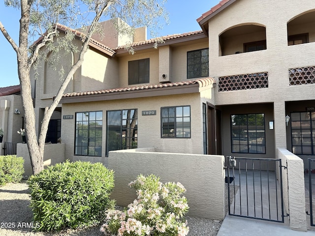 view of front of property featuring a gate, a tiled roof, stucco siding, and a fenced front yard