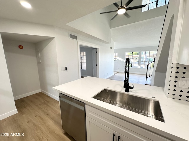kitchen featuring visible vents, baseboards, light countertops, a sink, and dishwasher