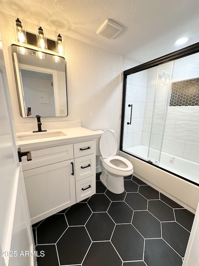 bathroom featuring shower / bath combination with glass door, vanity, a textured ceiling, and visible vents