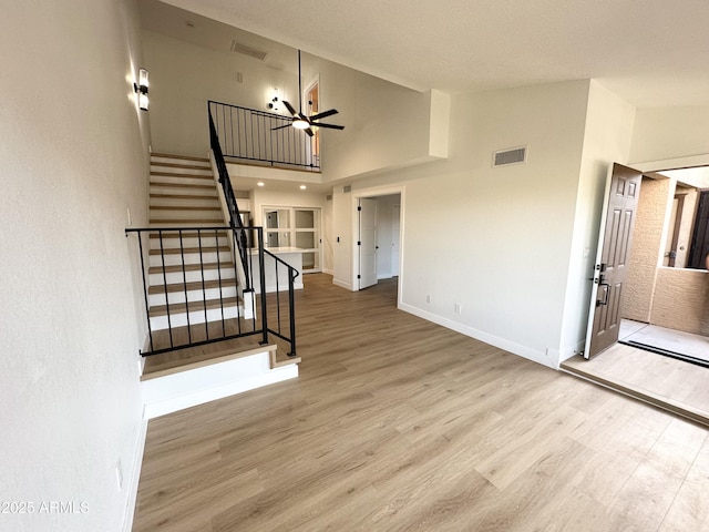 unfurnished living room with stairway, high vaulted ceiling, wood finished floors, and visible vents