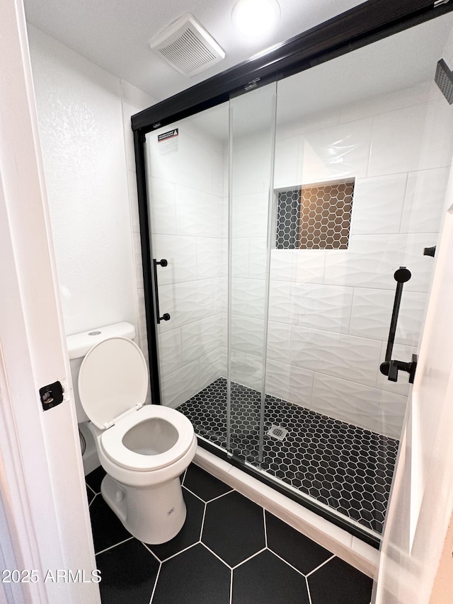 bathroom with toilet, tile patterned floors, visible vents, and a stall shower