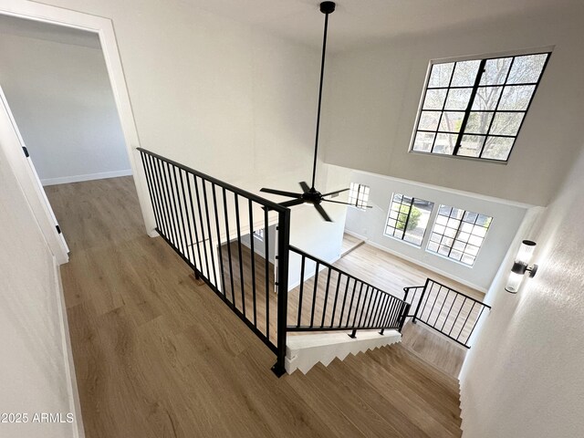 staircase featuring baseboards, ceiling fan, and wood finished floors