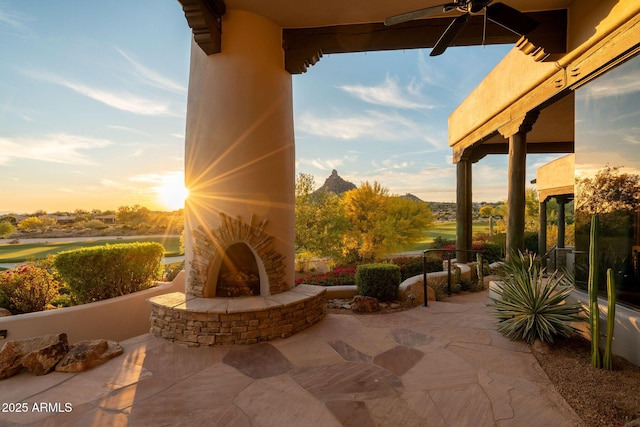 view of patio featuring a mountain view, an outdoor stone fireplace, and ceiling fan