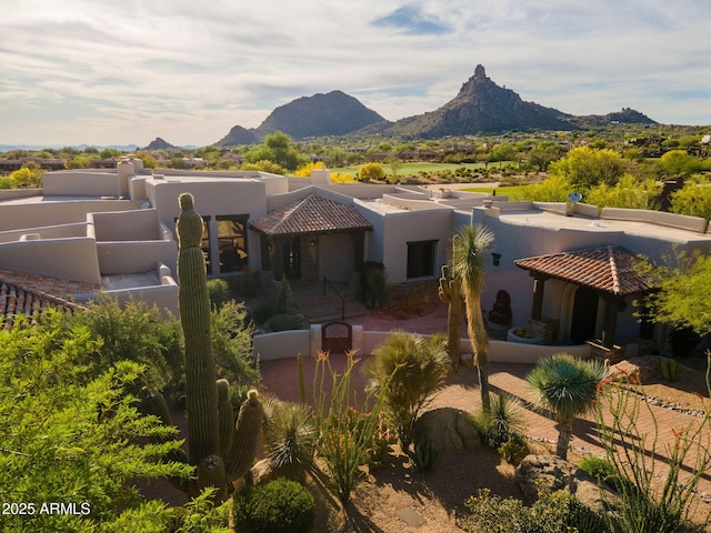 view of front of property with fence private yard, a tile roof, stucco siding, and a mountain view