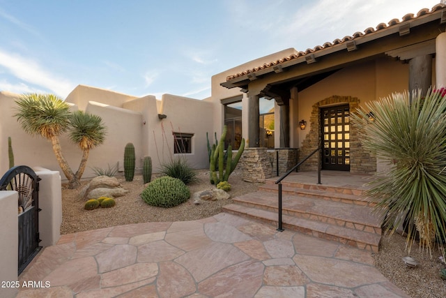 entrance to property with french doors, a tiled roof, and stucco siding
