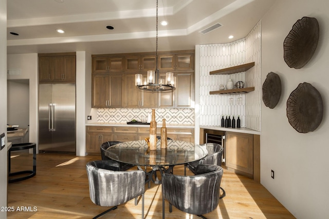 dining area with a chandelier, wine cooler, visible vents, and light wood-style floors