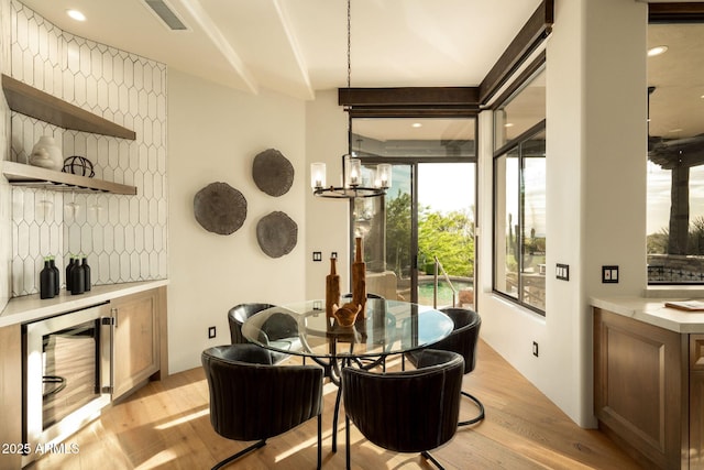 dining space featuring a chandelier, light wood-style flooring, visible vents, and wine cooler