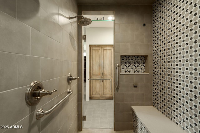 bathroom with a tile shower, tile patterned floors, and tile walls