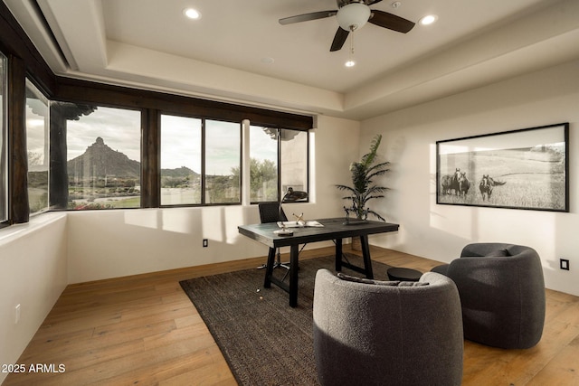 office with a tray ceiling, light wood-style floors, a ceiling fan, and recessed lighting