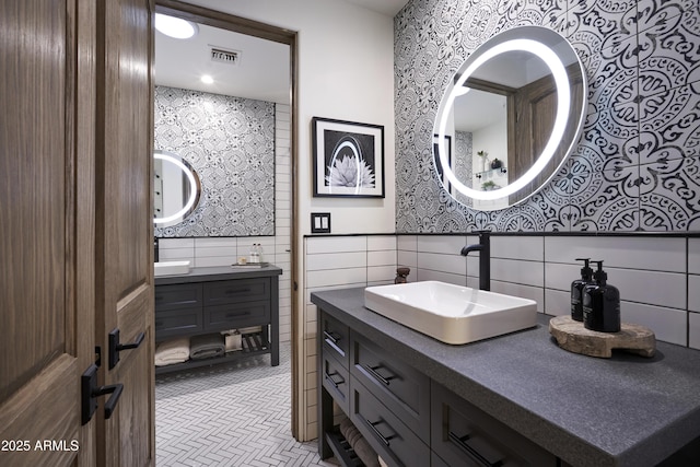 bathroom featuring vanity, visible vents, and tile walls