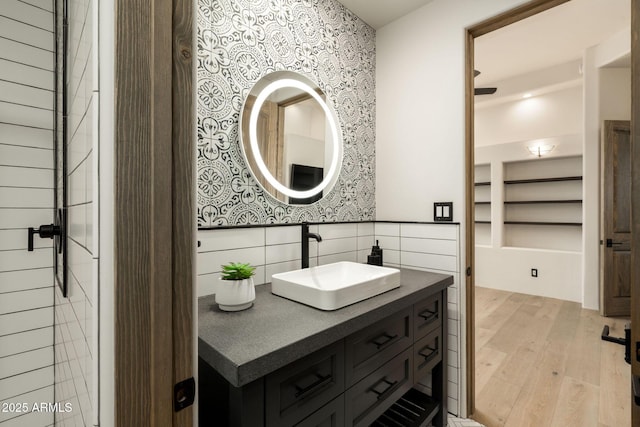 bathroom featuring vanity, wood finished floors, and wallpapered walls