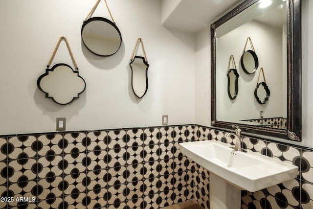 bathroom with wainscoting, tile walls, and a sink