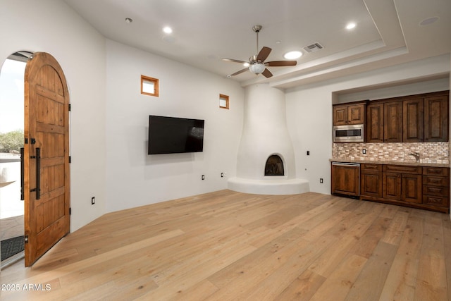 unfurnished living room with recessed lighting, visible vents, a sink, light wood-style floors, and ceiling fan