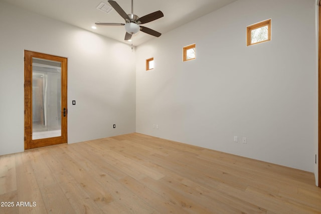 spare room with ceiling fan, a wealth of natural light, wood-type flooring, and visible vents