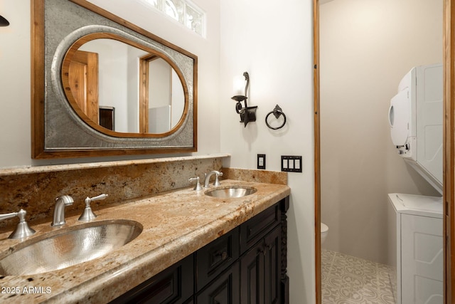 full bathroom featuring stacked washer / drying machine, double vanity, toilet, and a sink