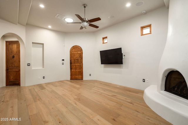living room featuring light wood finished floors, arched walkways, visible vents, recessed lighting, and a ceiling fan
