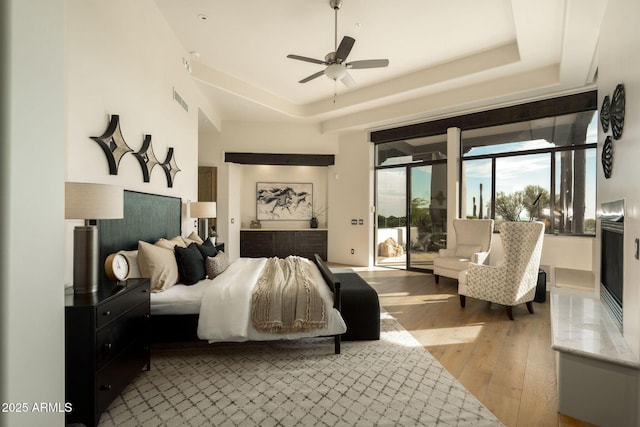 bedroom featuring a raised ceiling, light wood-type flooring, visible vents, and access to outside