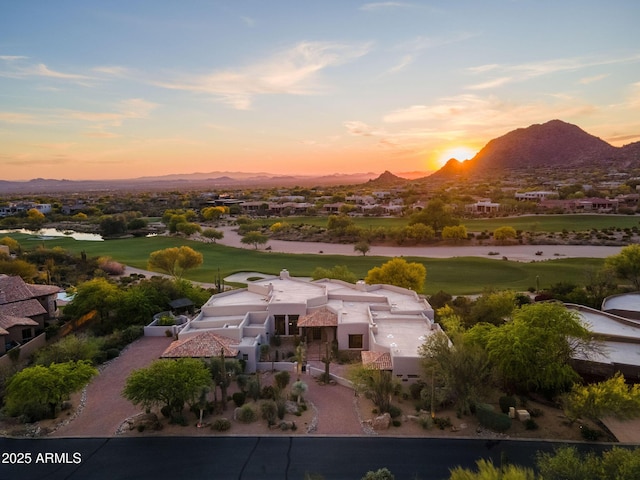 aerial view at dusk featuring golf course view and a mountain view
