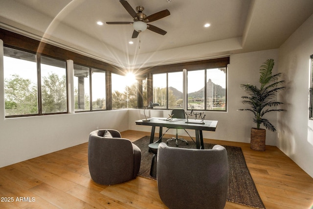 office space with ceiling fan, recessed lighting, a tray ceiling, and light wood-style floors