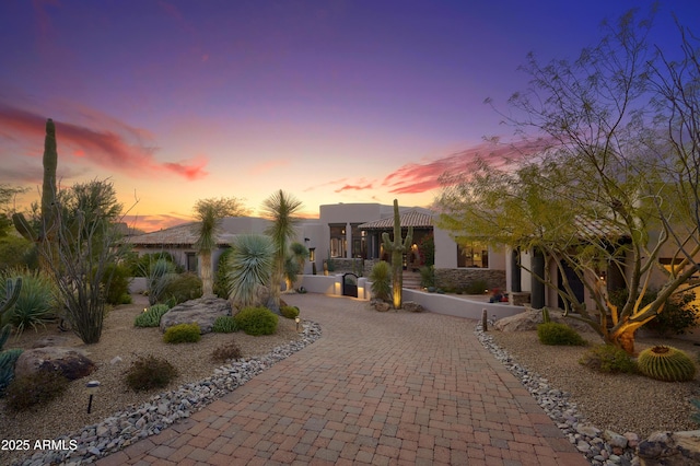pueblo revival-style home featuring stucco siding and curved driveway