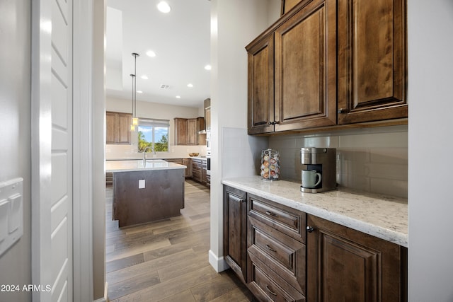 kitchen featuring tasteful backsplash, wood finished floors, a center island, a sink, and recessed lighting