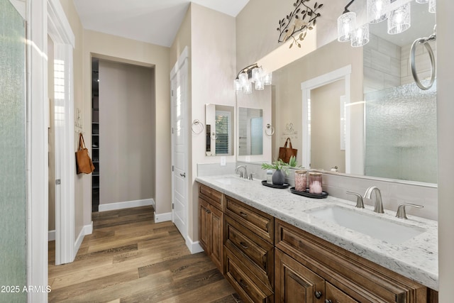 full bathroom featuring double vanity, wood finished floors, a sink, and baseboards