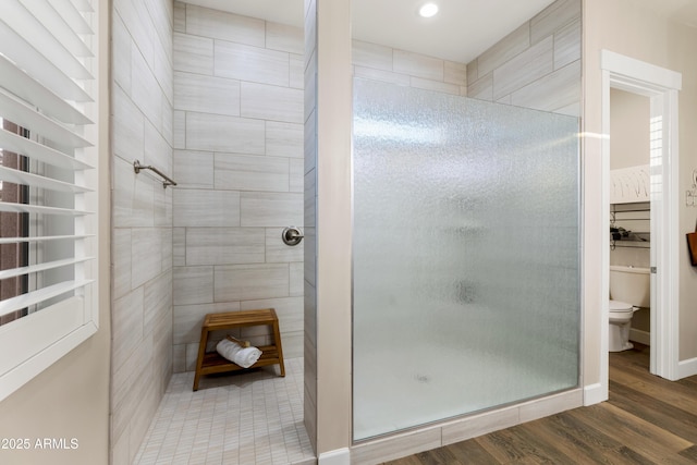 bathroom featuring a stall shower, wood finished floors, and toilet