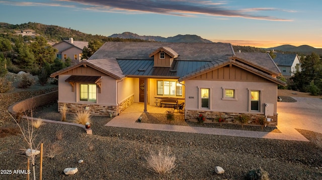 view of front of house with stone siding, a mountain view, a standing seam roof, and stucco siding