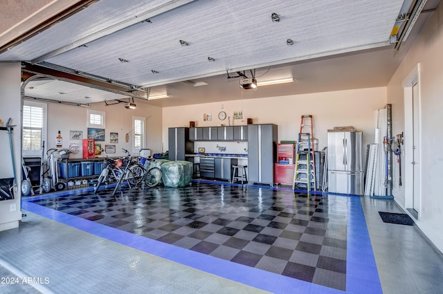 garage with a garage door opener and freestanding refrigerator