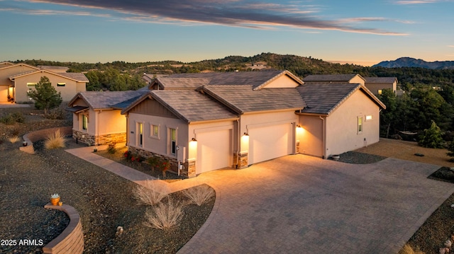 view of front of home featuring a garage, stone siding, driveway, and stucco siding