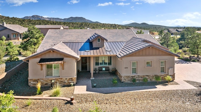 view of front of house featuring stone siding, metal roof, a standing seam roof, and a mountain view