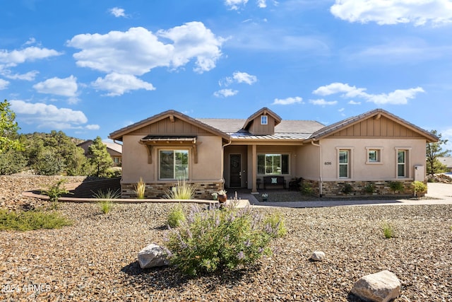 ranch-style house featuring stone siding, stucco siding, metal roof, and a standing seam roof