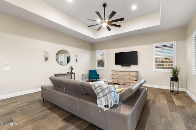 living area with ceiling fan, recessed lighting, dark wood-style flooring, baseboards, and a raised ceiling