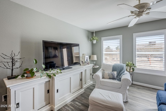 sitting room with ceiling fan, baseboards, and wood finished floors