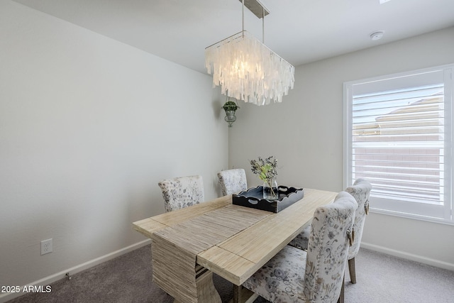 carpeted dining room featuring a notable chandelier and baseboards