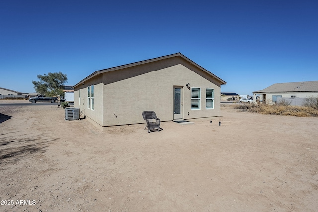 rear view of house with central air condition unit and stucco siding