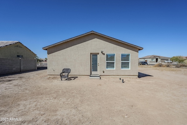 rear view of house with fence and stucco siding