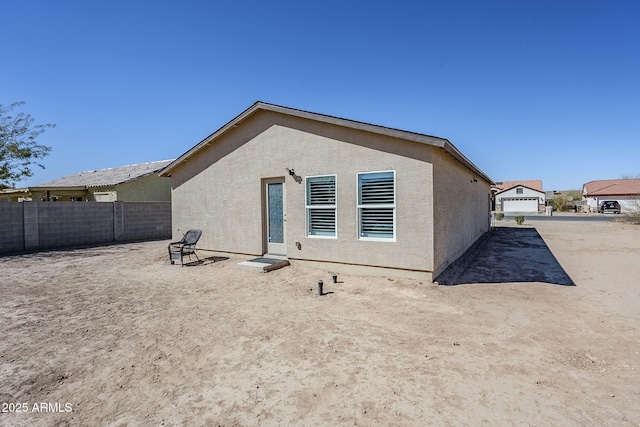 rear view of house featuring fence and stucco siding