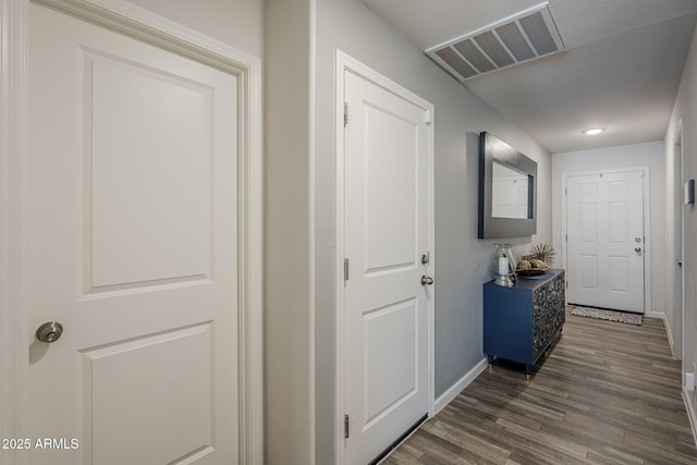 hallway featuring dark wood-type flooring, visible vents, and baseboards