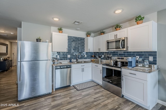 kitchen featuring a sink, visible vents, white cabinets, appliances with stainless steel finishes, and light wood finished floors