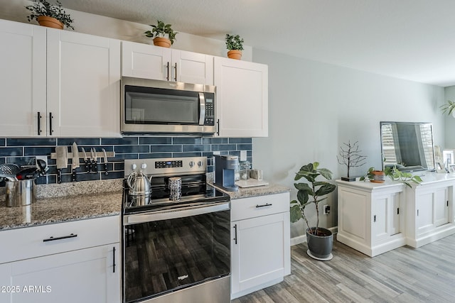 kitchen with appliances with stainless steel finishes, white cabinetry, and backsplash