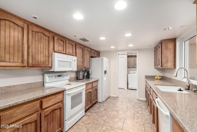 kitchen with light stone counters, sink, white appliances, and washer / clothes dryer