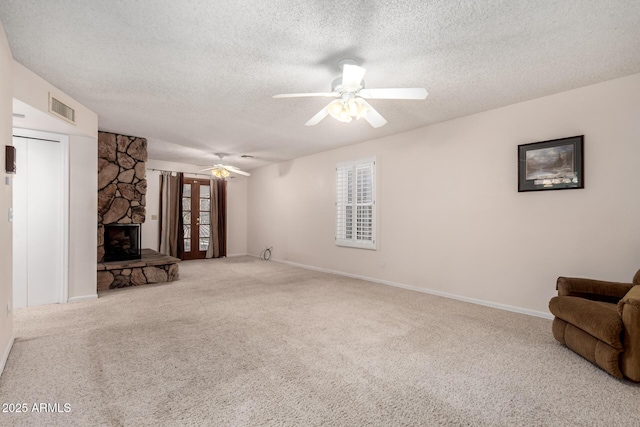 unfurnished living room with carpet floors, a textured ceiling, ceiling fan, and a fireplace